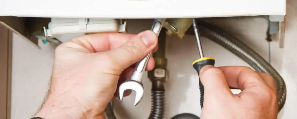 Boiler repair technician tightening pipe fittings and connections in Omaha, NE