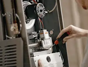 Furnace repair technician inspecting internal components and wiring in Omaha, NE
