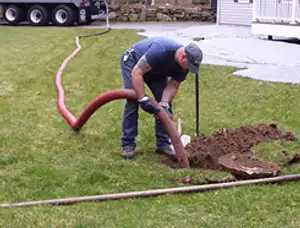 Septic pumping technician servicing a residential septic tank with a vacuum hose in Omaha, NE