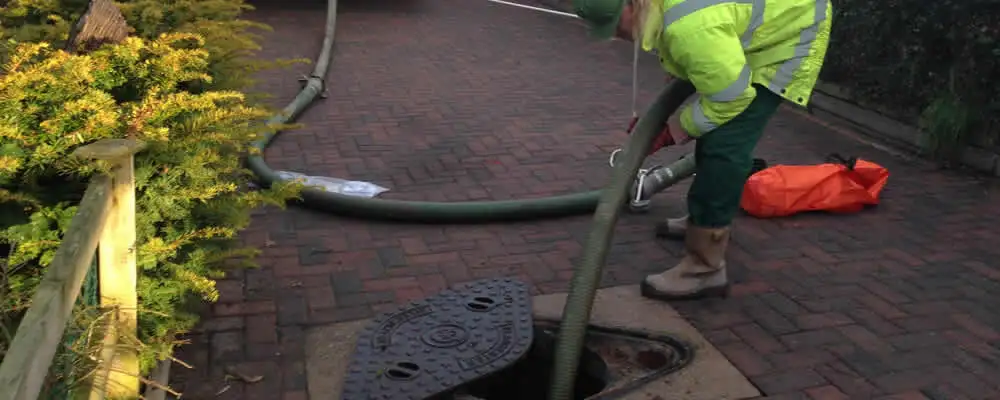 Septic tank cleaning technician servicing a septic tank with a vacuum hose in Omaha, NE