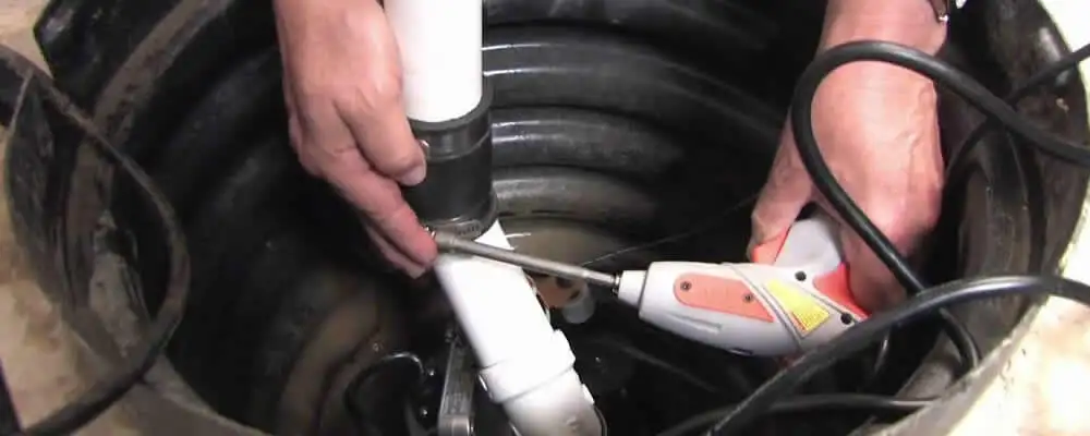 Sump pump installation technician connecting PVC discharge piping in Omaha, NE