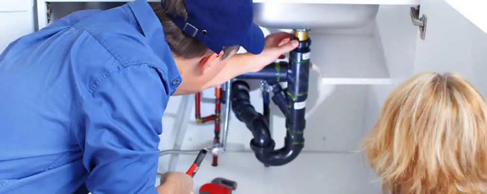 Plumber repairing under-sink drain pipes and fittings in Omaha, NE
