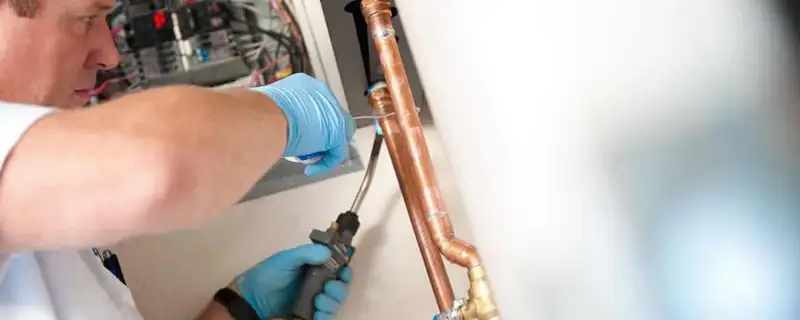 Water heater repair technician testing copper pipe connections and controls in Omaha, NE